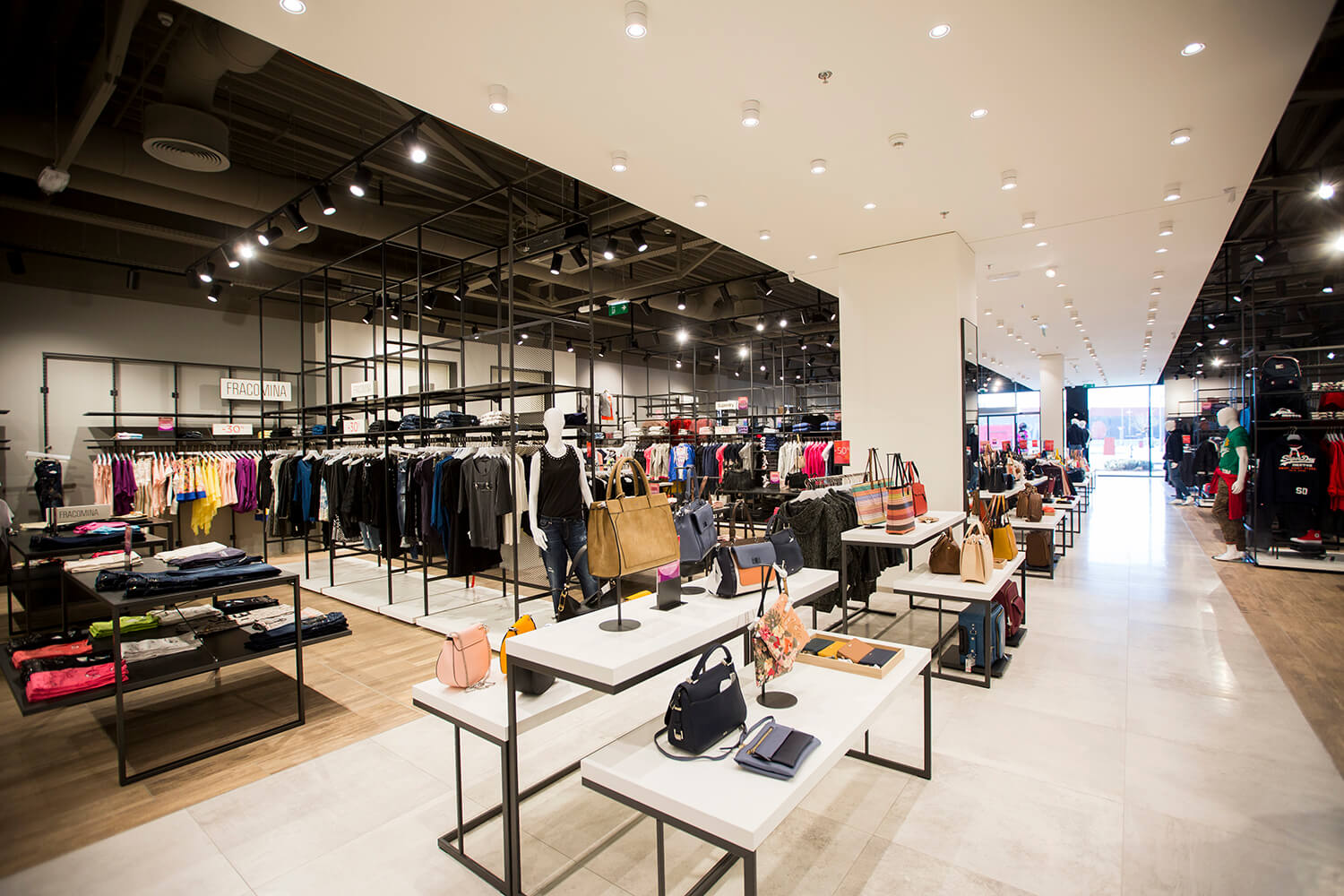 Bel strop z lučkami in belo črnimi regali v trgovini Sportina Outlet