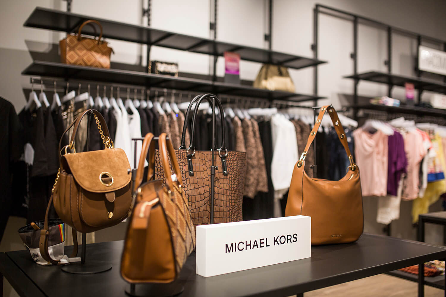 Torbice Michael Kors na črnem regalu v trgovini Sportina Outlet