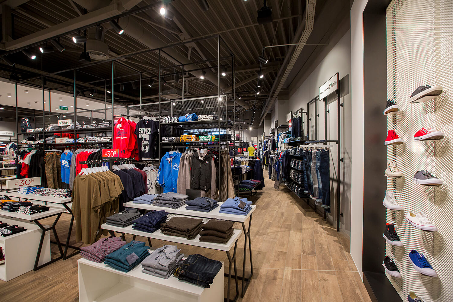 Beli regali na črnem ogrodju in stena s čevlji v trgovini Sportina Outlet